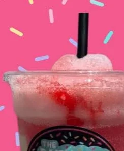 A Dairy Duck float in a clear cup with a black straw, red syrup swirled through the top