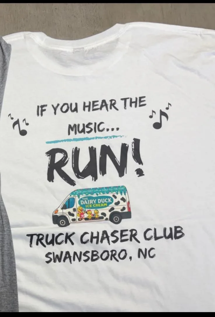 The back of the tee: music notes around the words If you hear the music, RUN in brush lettering, above the cow-spotted Dairy Duck ice cream van and the words Truck Chaser Club, Swansboro, NC