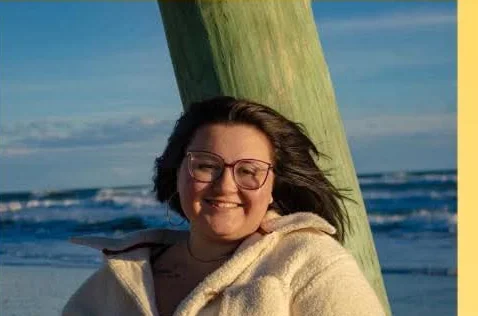 Tori, a Dairy Duck truck operator, standing on the beach at sunset